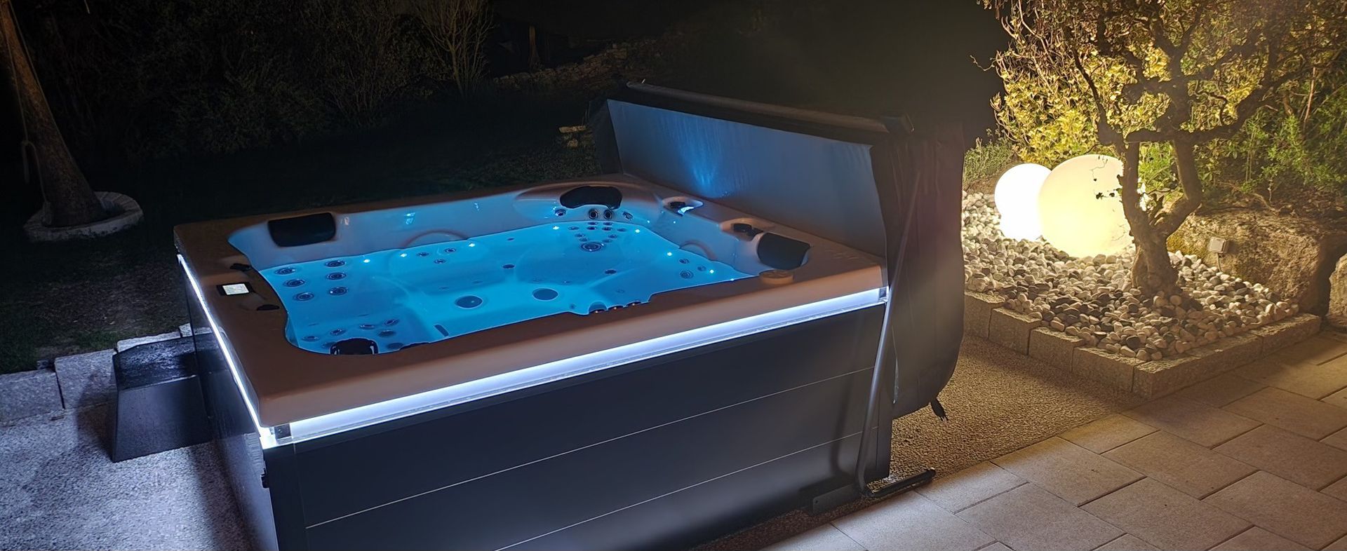 Un jacuzzi est éclairé la nuit dans un jardin.