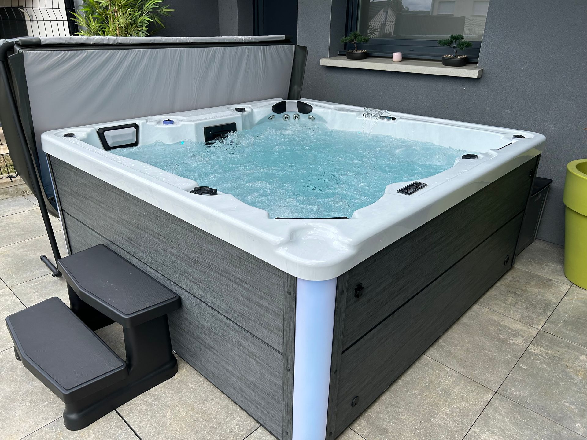 Un bain à remous est installé sur une terrasse à côté d'une fenêtre.