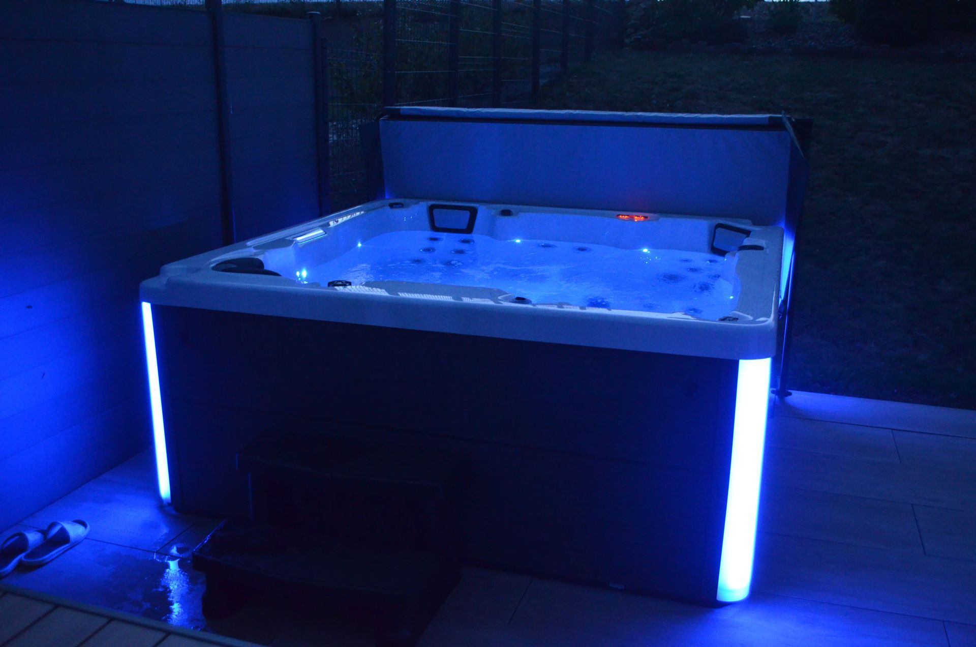 Un bain à remous est éclairé par des lumières bleues la nuit.