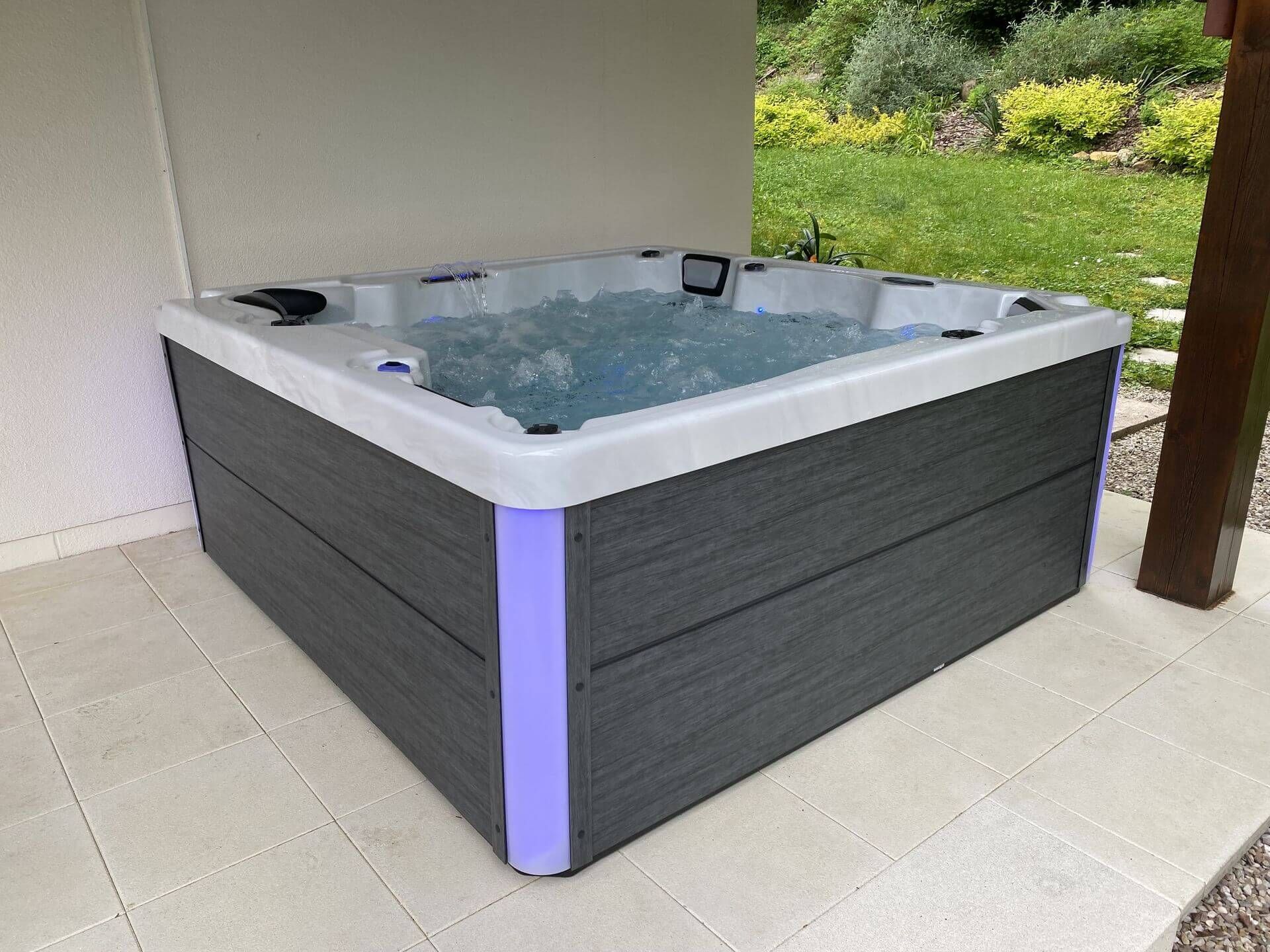 Un jacuzzi gris et blanc est posé sur un sol carrelé.