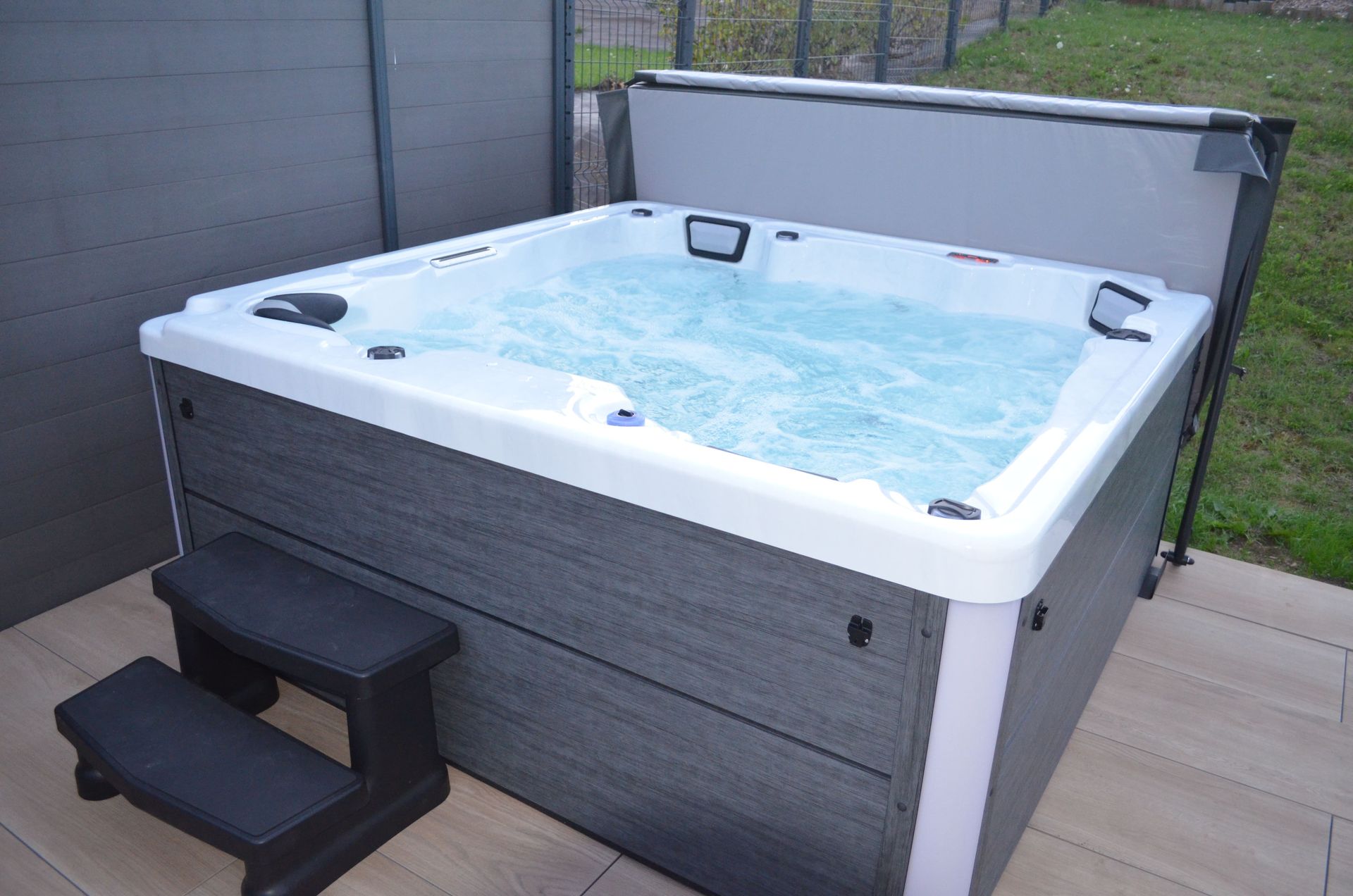 Un jacuzzi blanc et gris avec de l'eau bleue et des marches