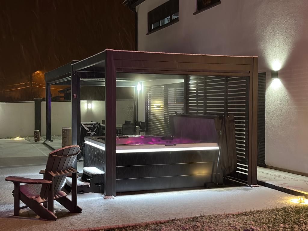 Un jacuzzi est installé sous une pergola dans une cour arrière la nuit.