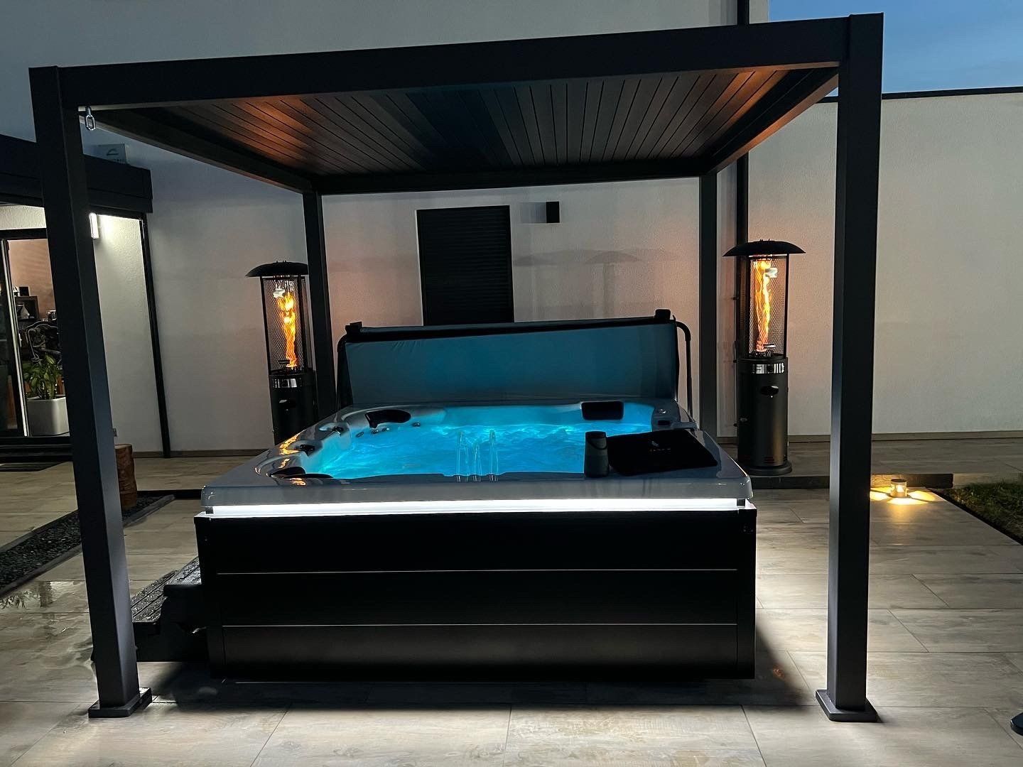 Un jacuzzi sous une pergola avec des lumières dessus