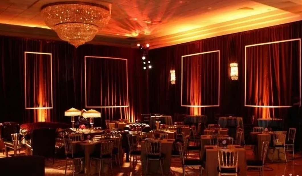 Elegant dining room with red curtains, tables, and chandelier lighting.
