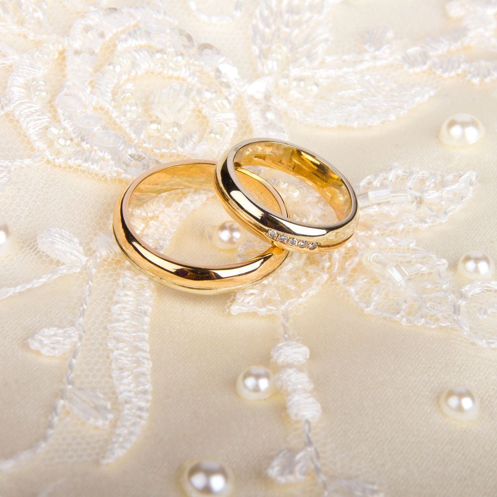 A pair of gold wedding rings on a white lace background - Jewellers in Dubbo, NSW