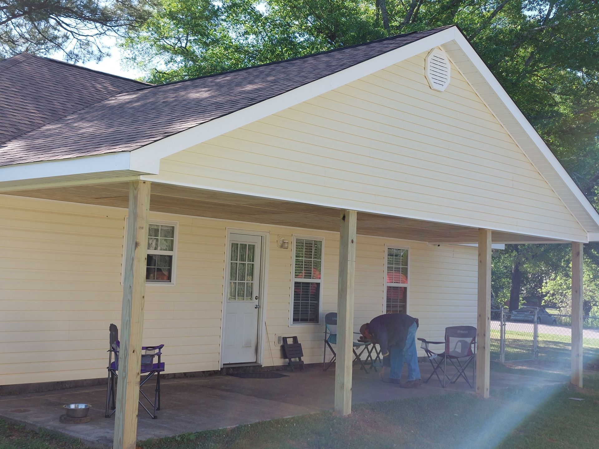 White house with a covered front porch, two chairs, and a small table under the roof overhang.