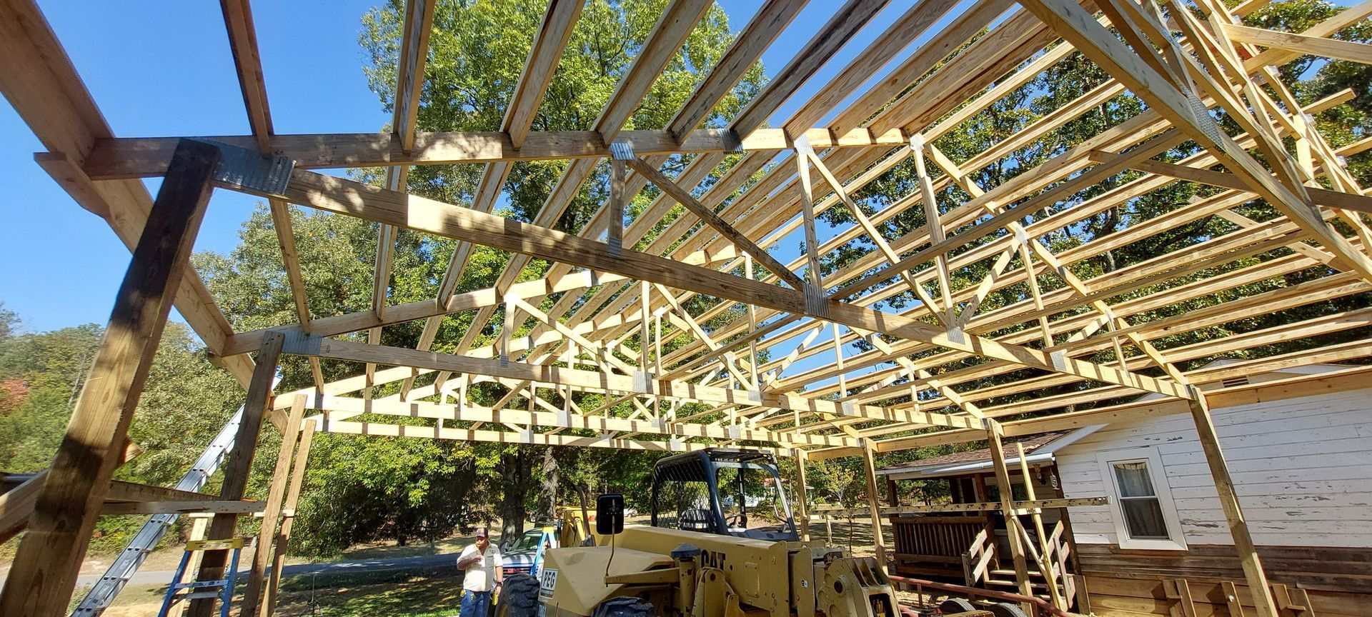 Outdoor wooden greenhouse frame under construction with beams, lattice roof, and workers below