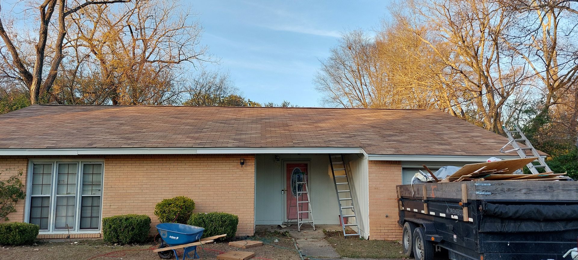 Single-story brick house with a front porch, tree-lined yard, and a pickup truck in the driveway