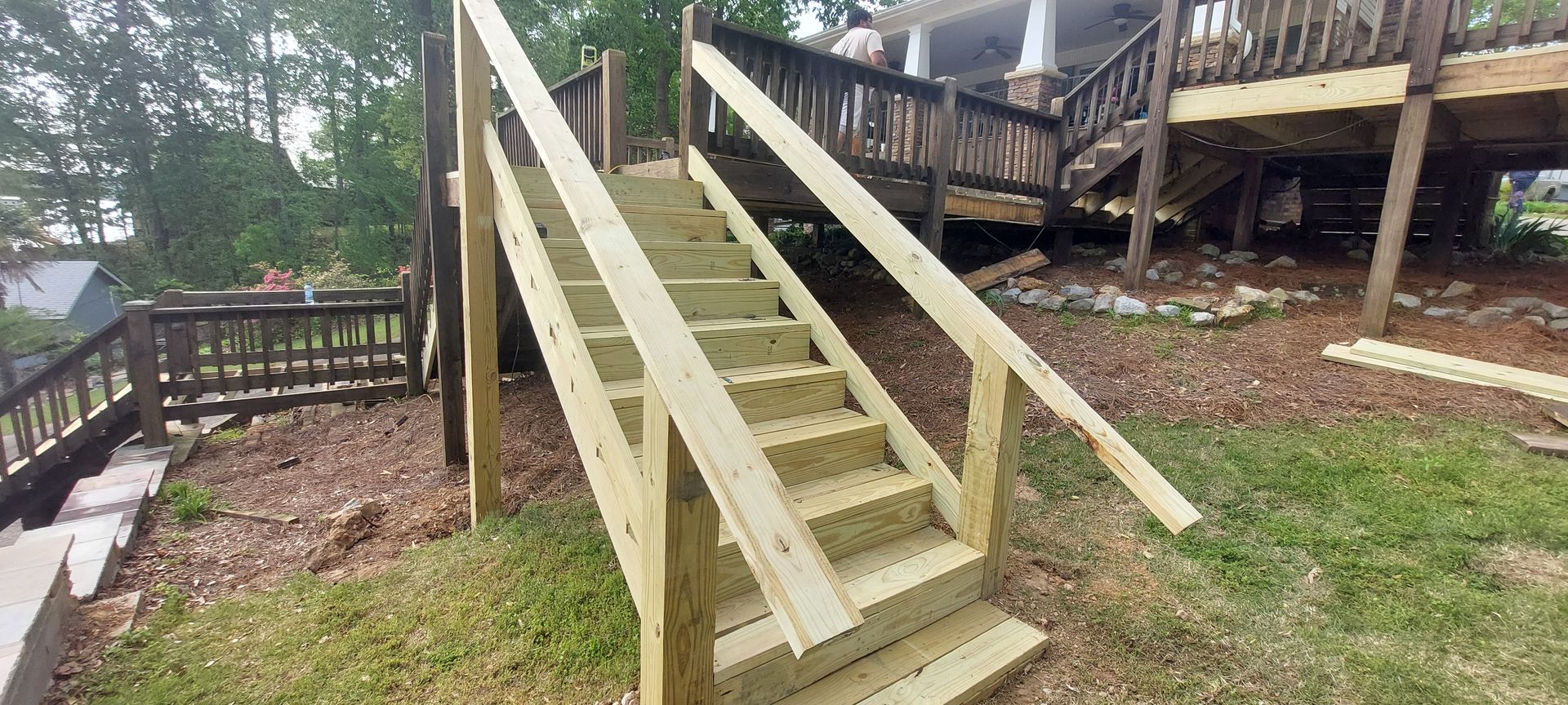 Wooden ramp with handrails leading up to a porch in a grassy yard, with steps beside it.