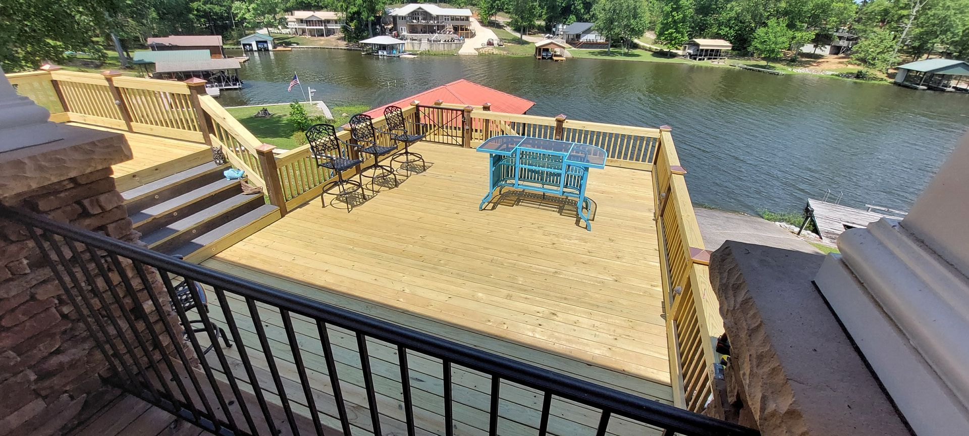 Rooftop patio with blue lounge chairs overlooking a river and green shoreline