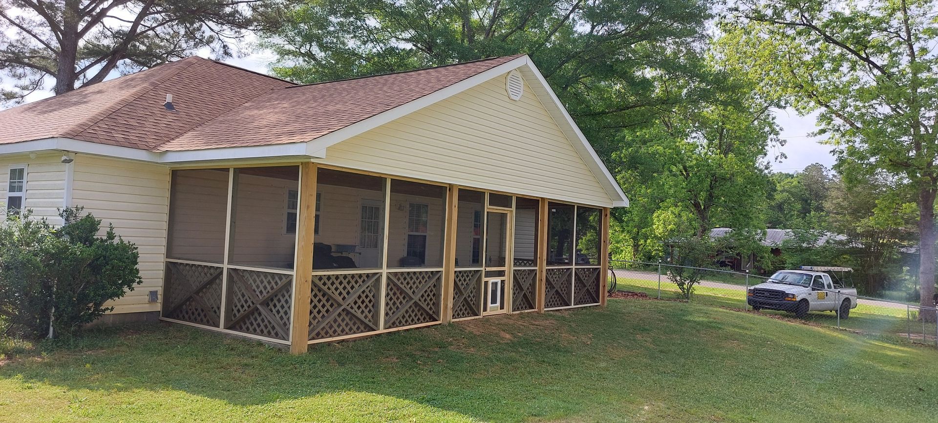Screened porch on a small house with a red tile roof and a parked car in the yard