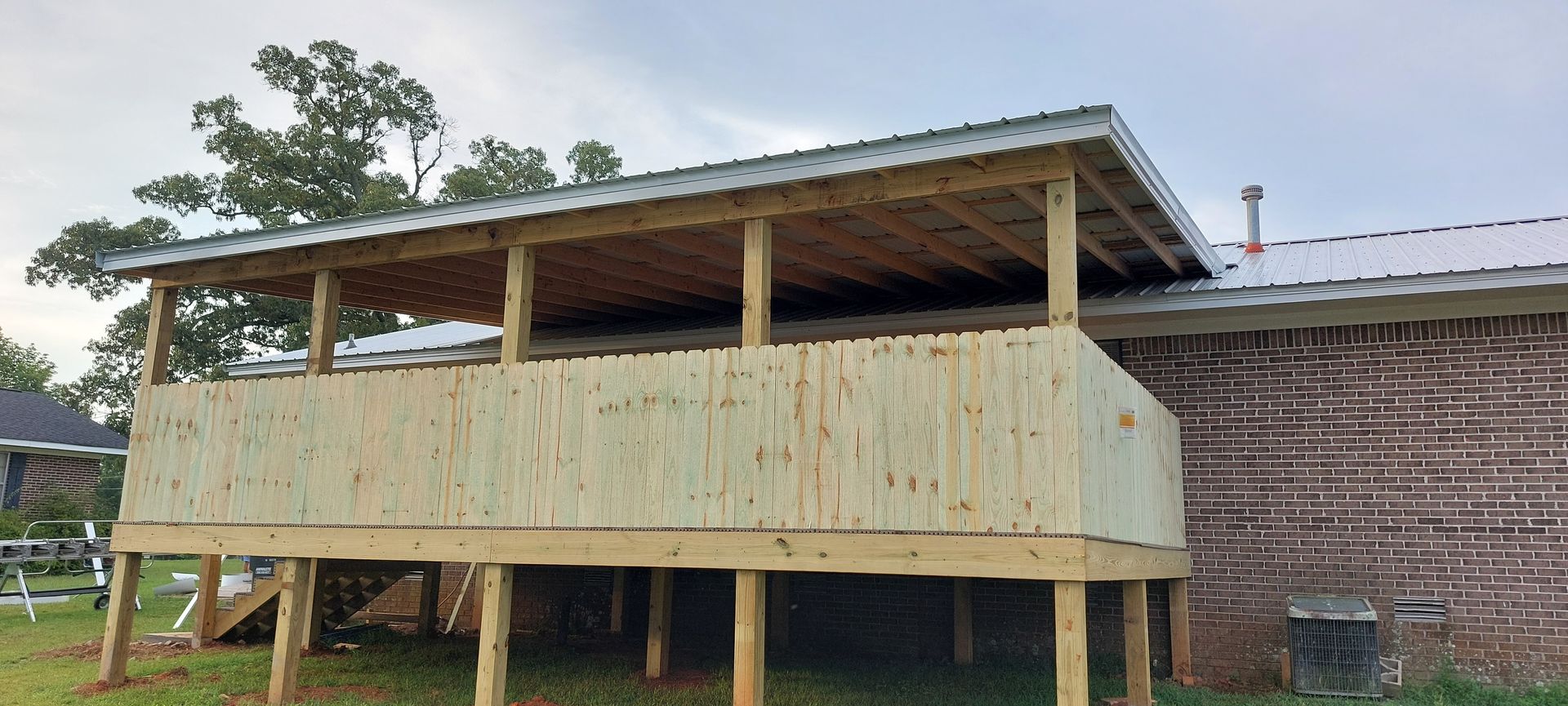 Raised wooden house with a wraparound porch under construction on stilts