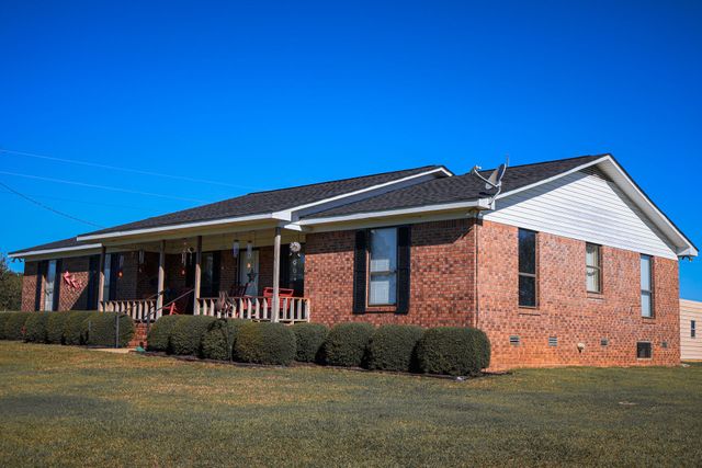 House exterior with a metal roof and chimney, ladders and tools set up for repairs under a covered porch