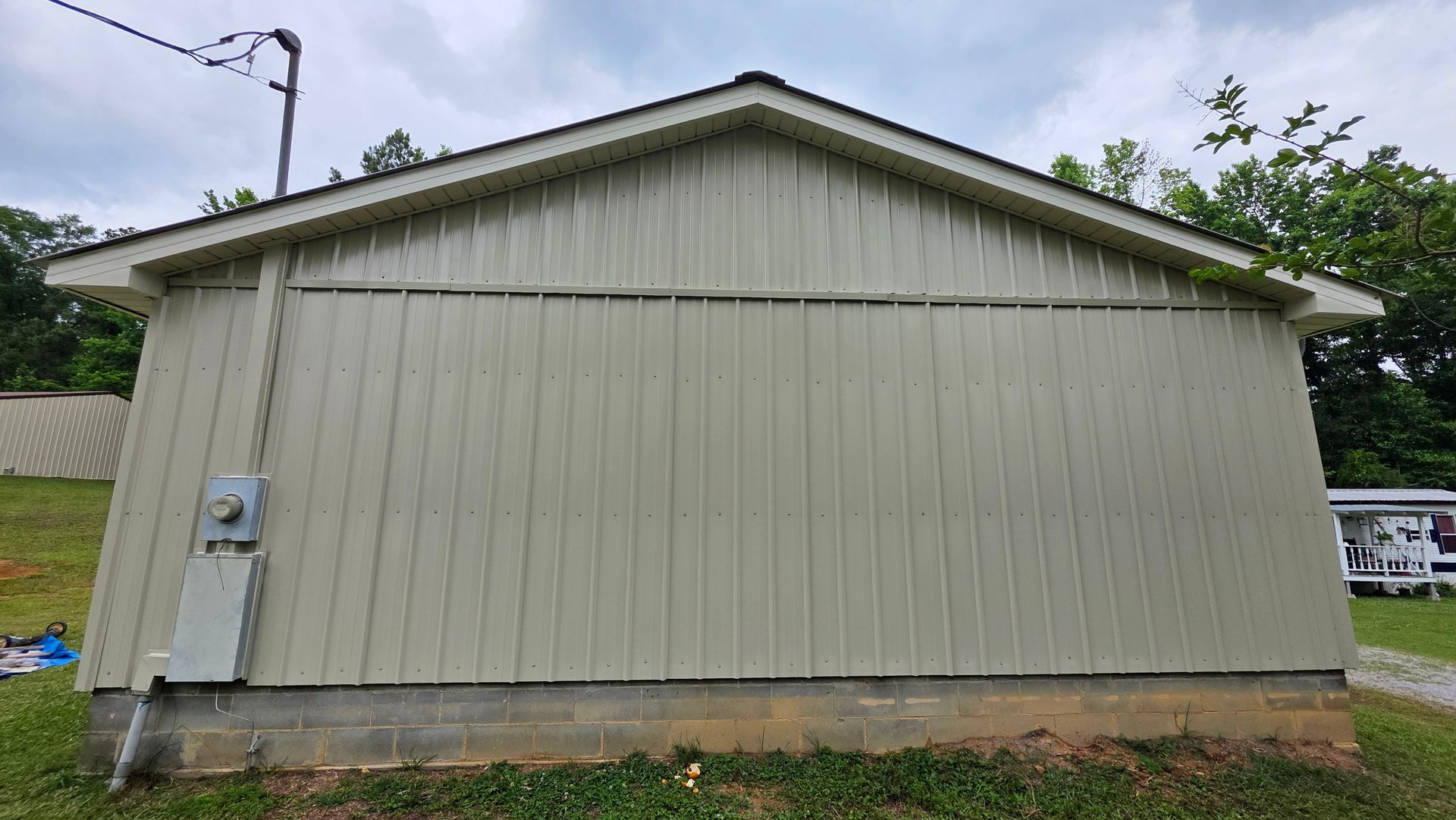 Beige house siding with a gabled roof and utility meter on the left side.