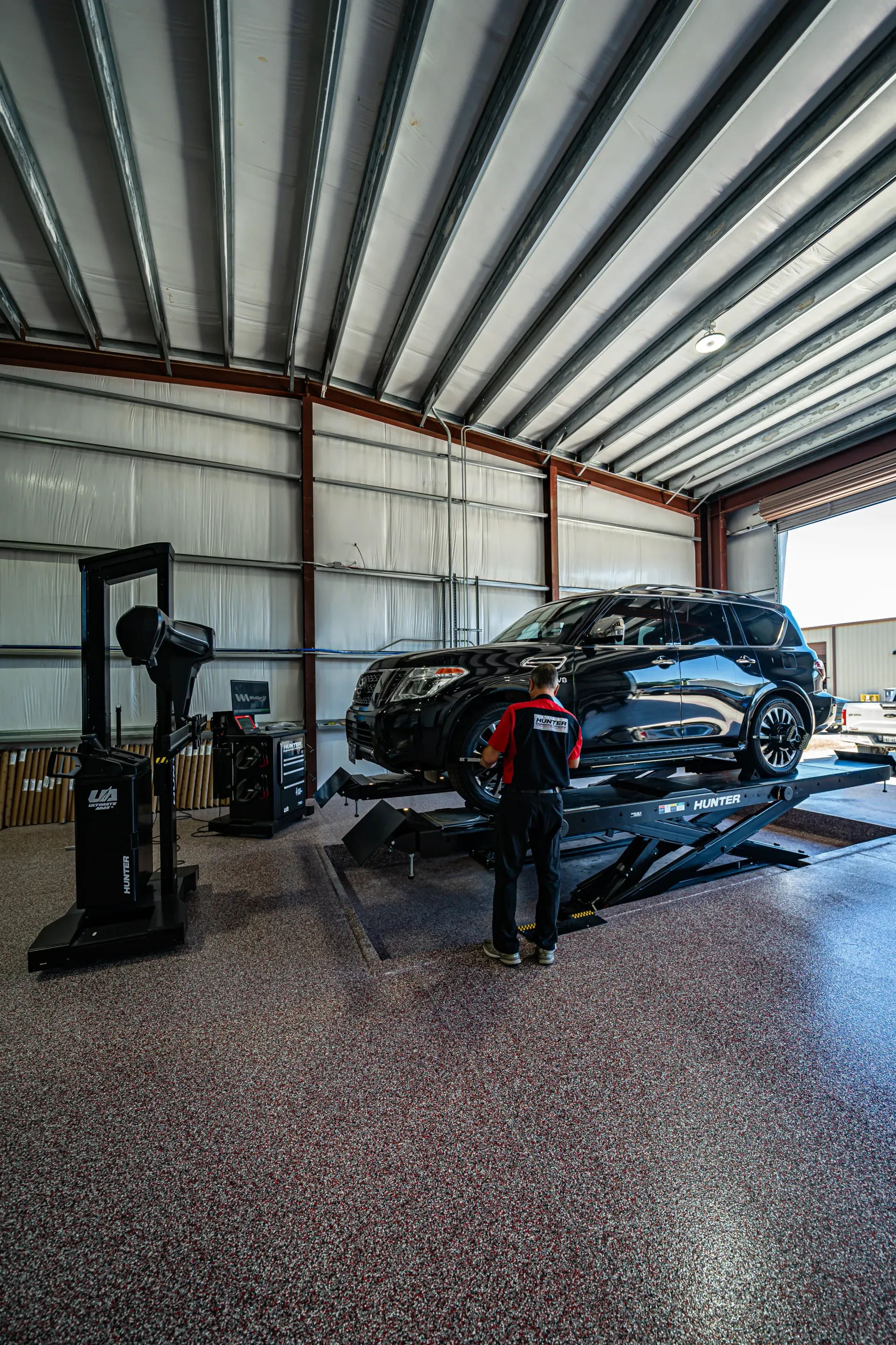 An SUV on a lift in a garage being serviced by a mechanic. The setting is indoors. | Advance Automotive