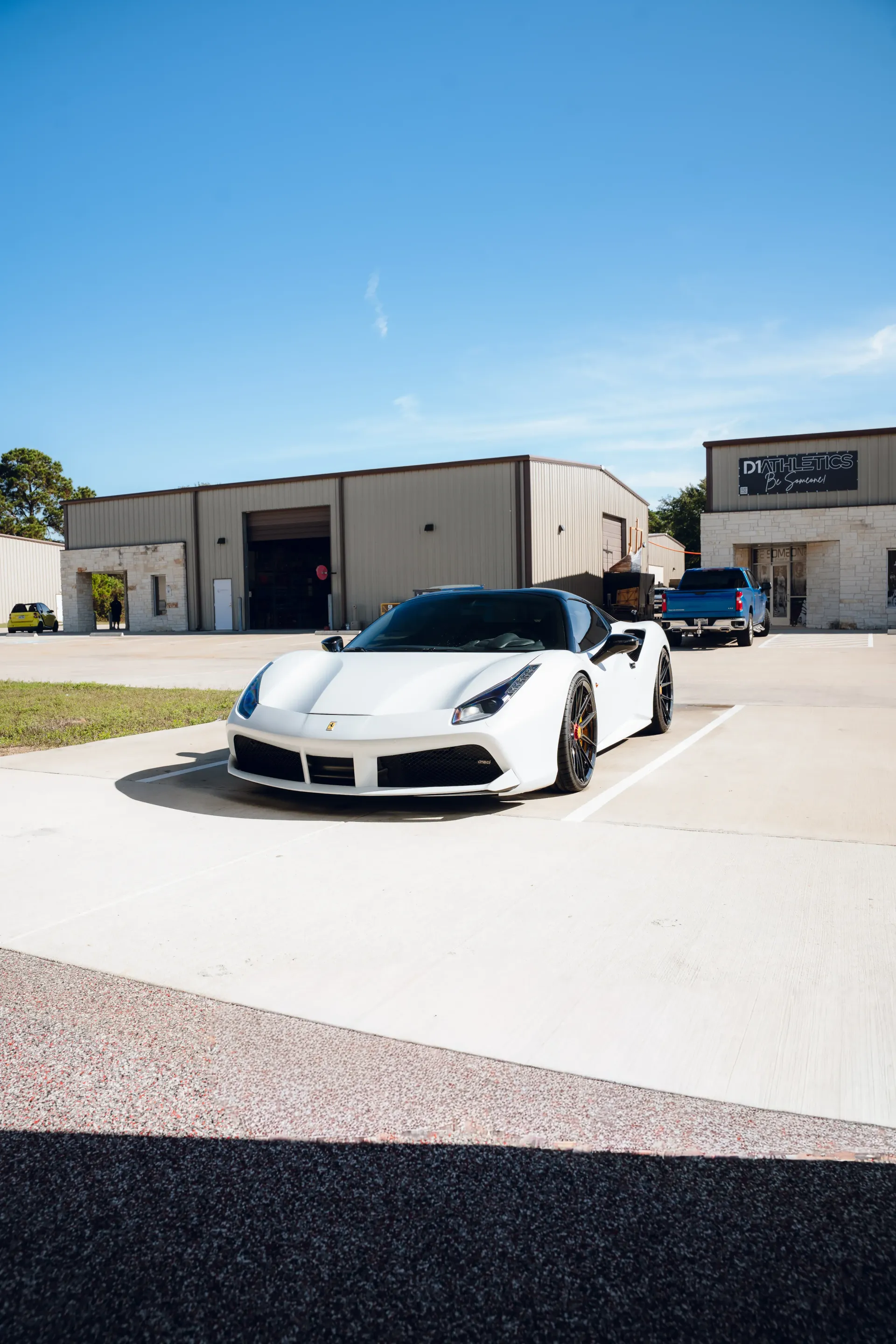 White Ferrari parked in front of industrial buildings under a bright blue sky. | Advance Automotive
