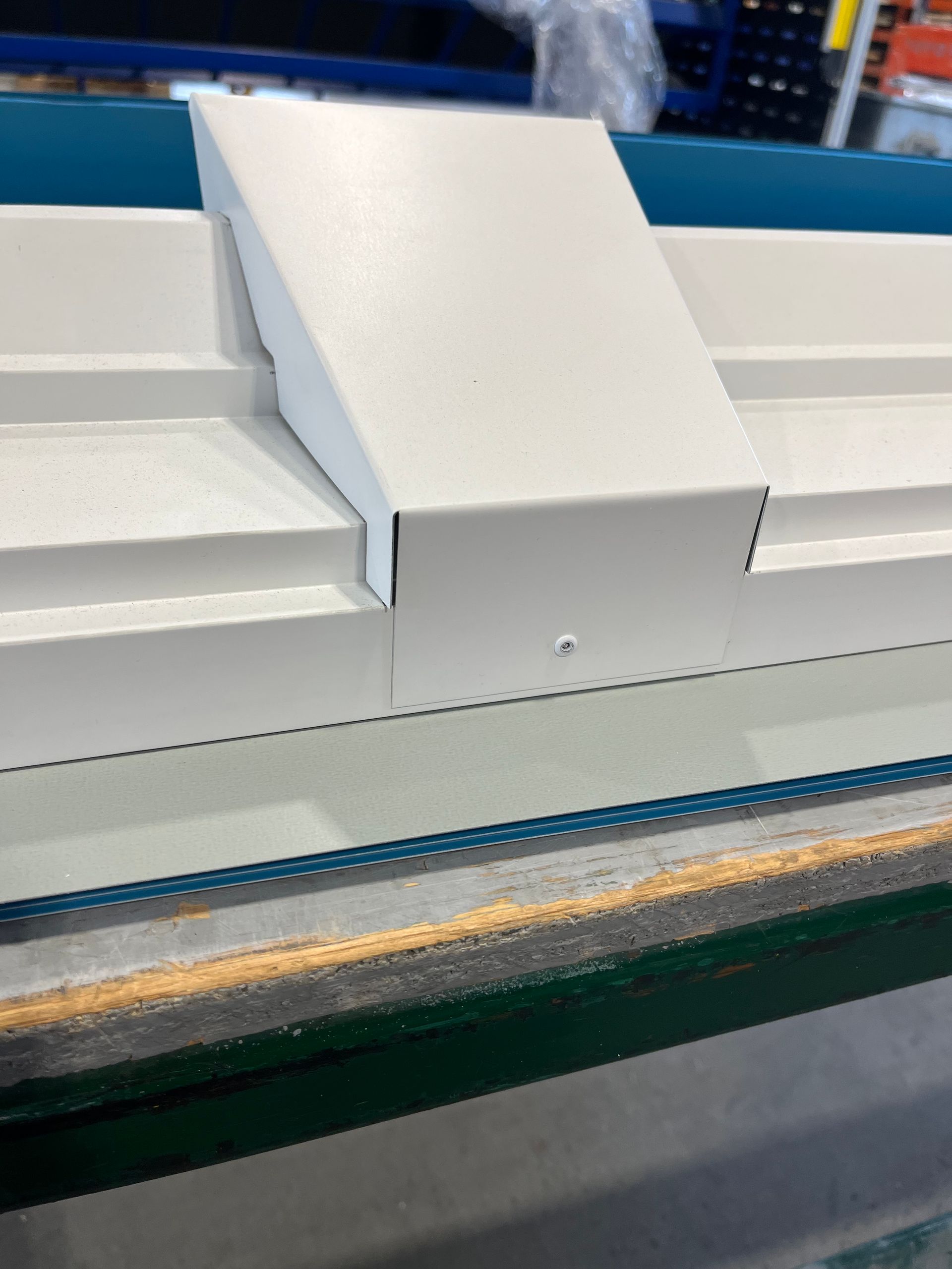 Machine industrielle blanche avec une goulotte centrale inclinée et des garnitures bleues sur une ligne de production