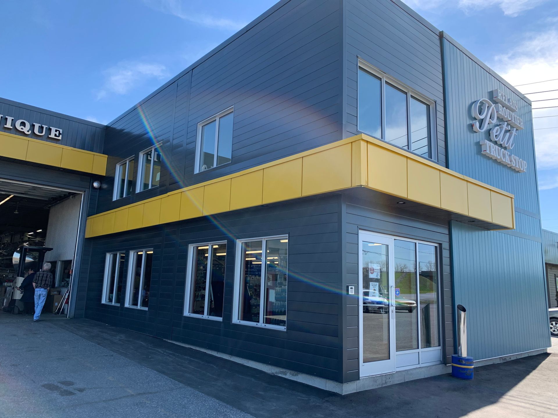 Façade moderne bleue et jaune avec de grandes fenêtres et une entrée d'angle