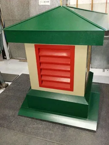 Petite structure à toit vert avec un panneau ventilé rouge et une base verte sur le sol d'un atelier