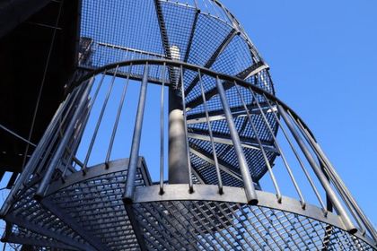 Metal spiral staircase against a bright blue sky