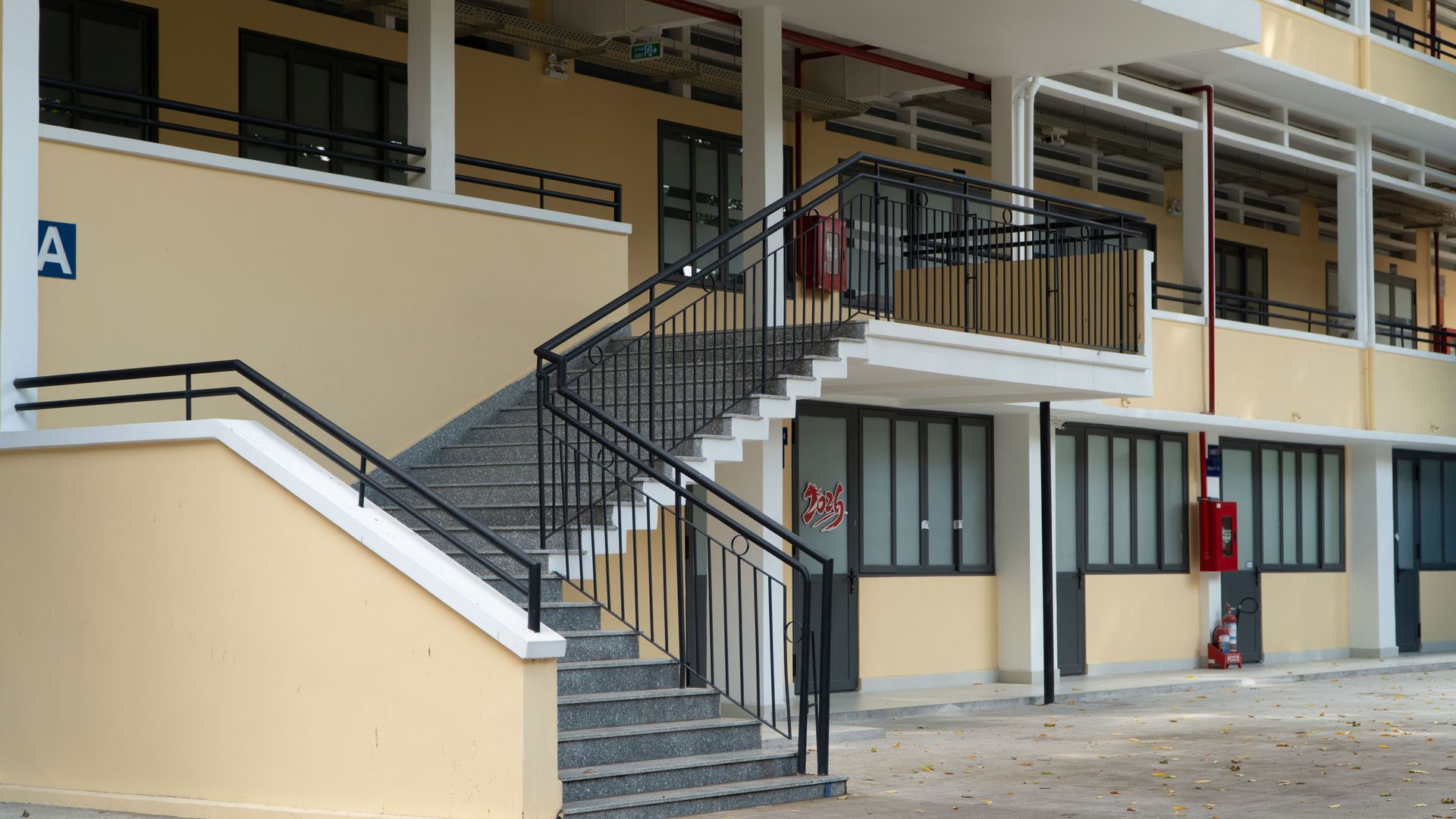 Outdoor stairway with black railings leading to a second-floor walkway in a beige Vail building courtyard