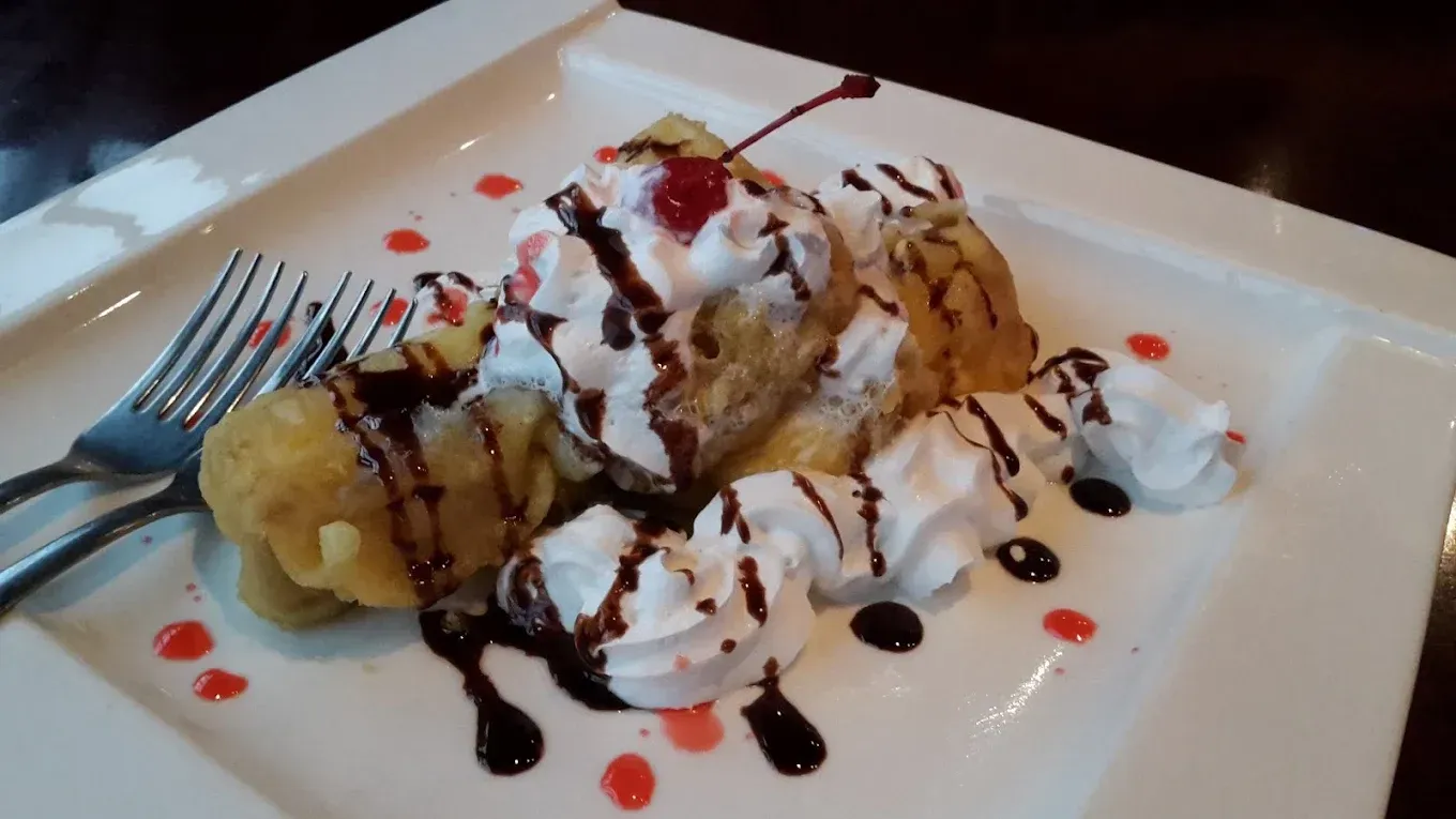 Dessert plate with a scoop of ice cream, whipped cream, and chocolate drizzle on a white plate