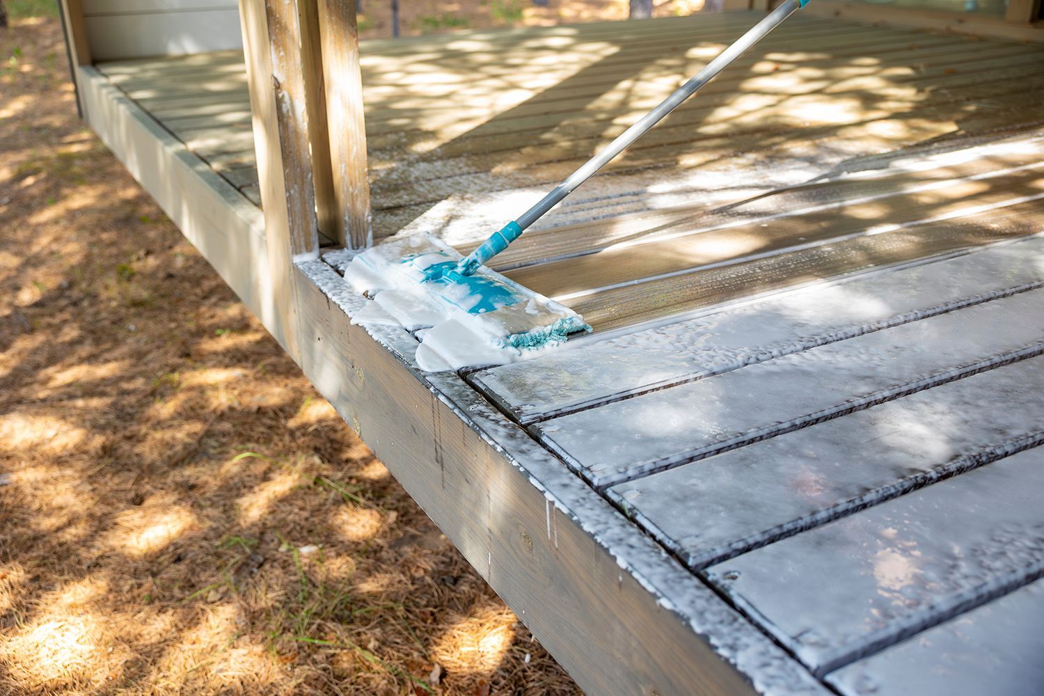 Wooden deck with white paint and a blue tape roll along the edge, outdoors in sunlight