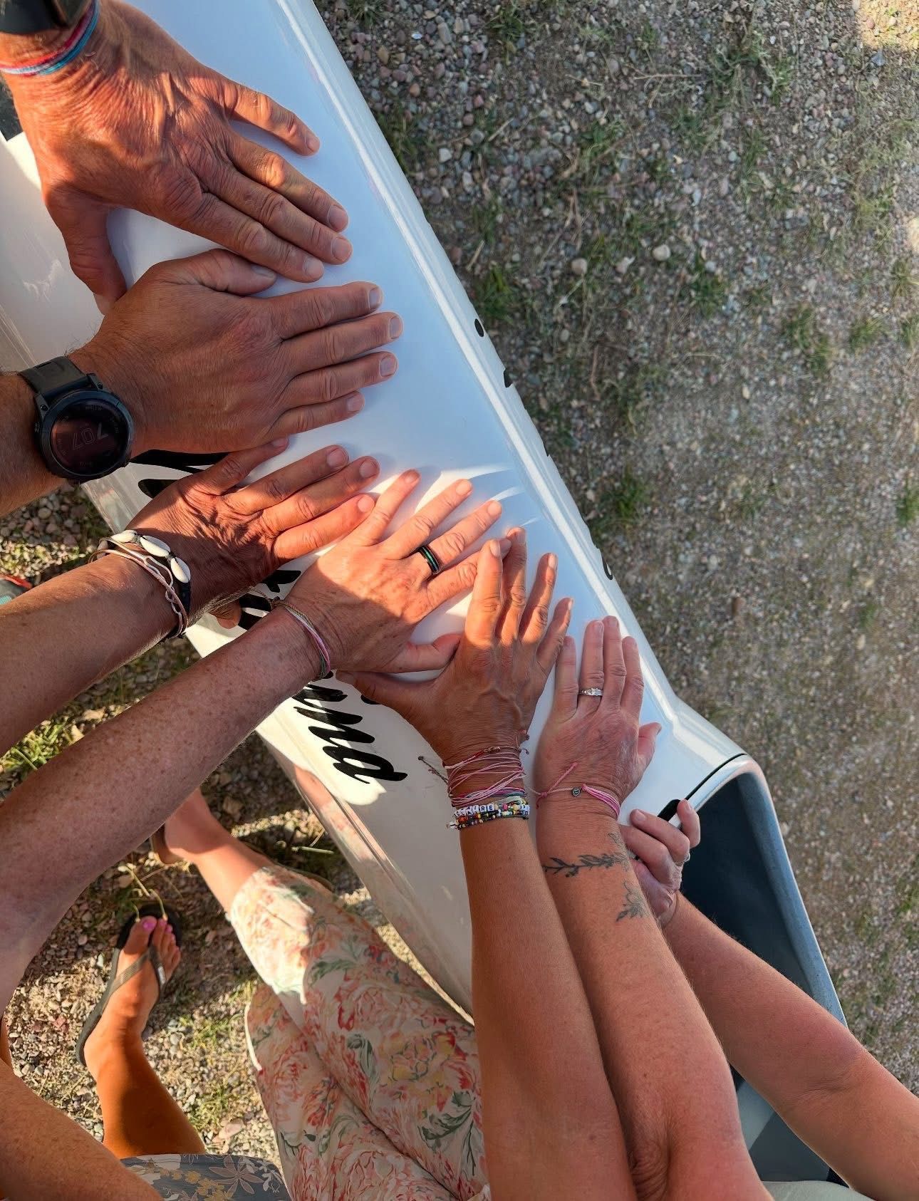 Hands of multiple people touching a white boat, possibly celebrating together.