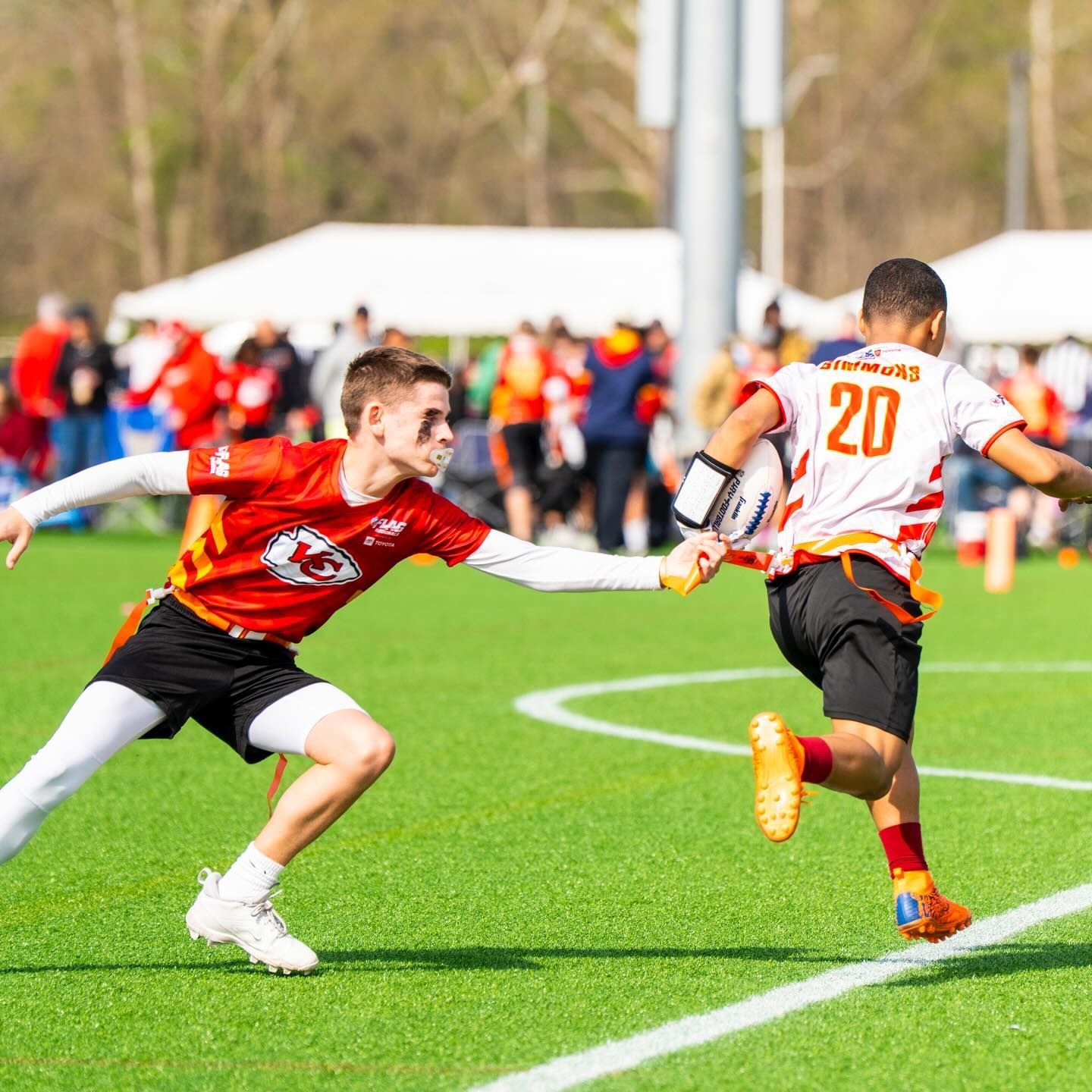 Young athlete running with a football in an NFL FLAG jersey.