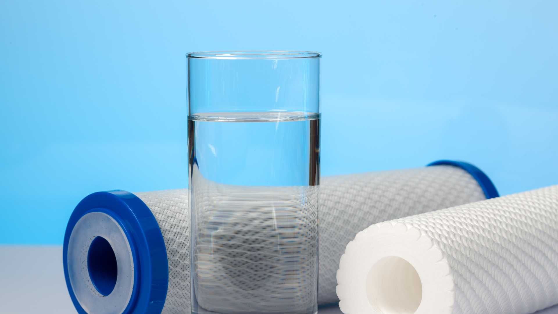 A glass of water is sitting next to two water filters.