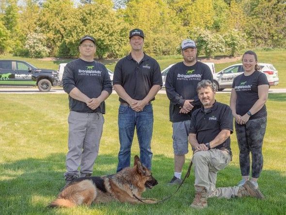 A group of people and a german shepherd are posing for a picture.