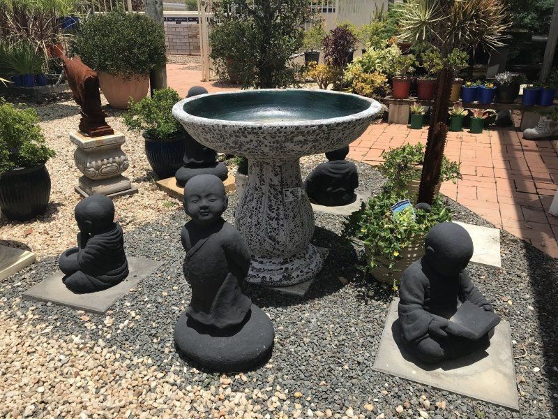 A Group of Statues Are Sitting Around a Bird Bath in a Garden — Golden City Brick & Landscape in Gympie, QLD