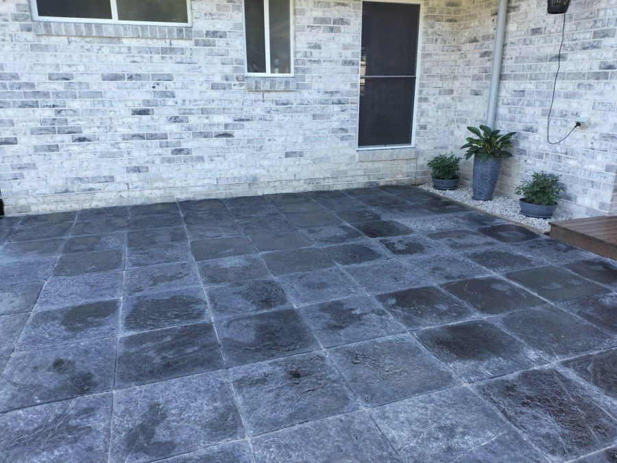 A Patio With Black Tiles in Front of a White Brick Building — Golden City Brick & Landscape in Gympie, QLD