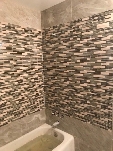 A bathroom with a bathtub and tiled walls.
