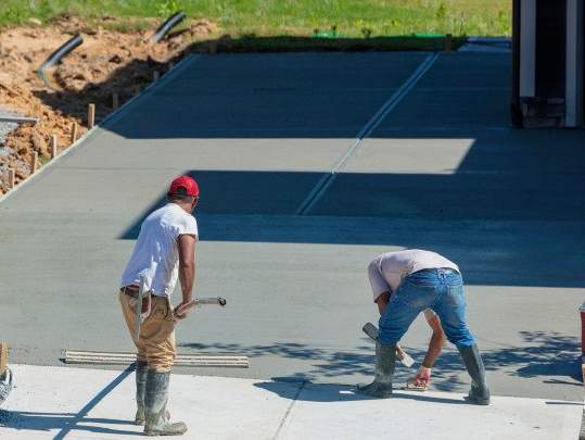 Two men are working on a concrete driveway.
