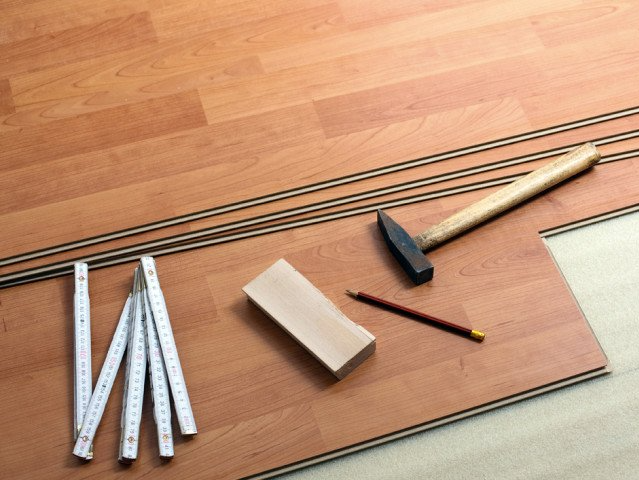 A wooden floor with a ruler a hammer and a pencil on it