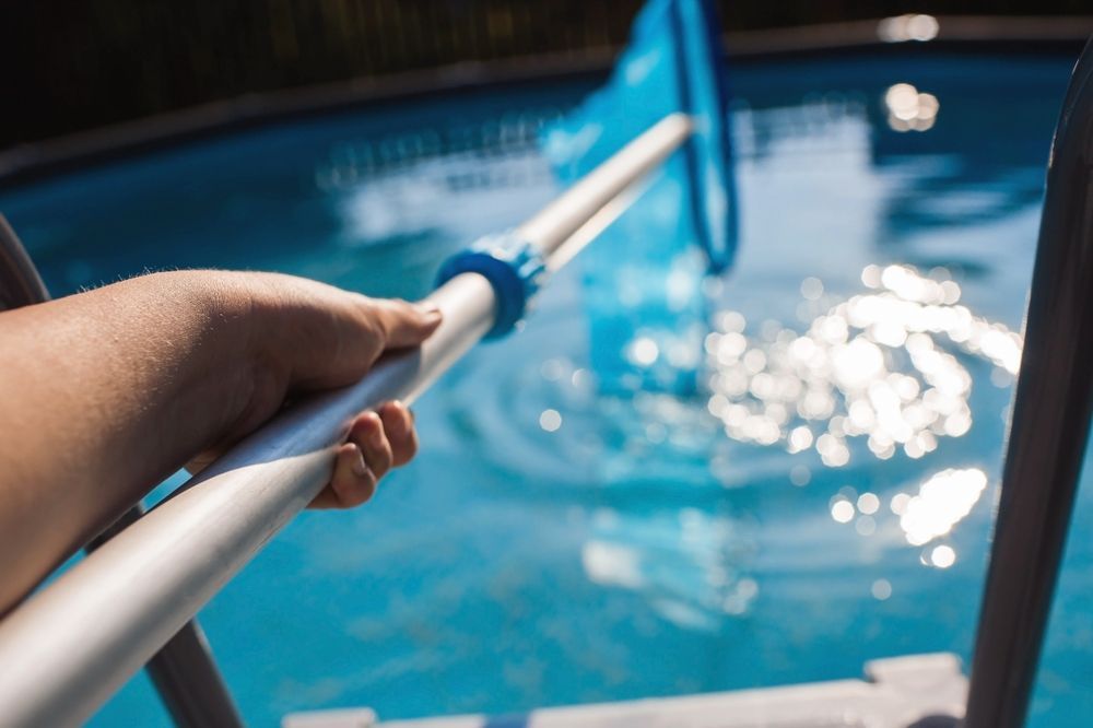 A First-person View of a Hand Holding a Blue Pool Skimmer — Sun Cool Pools & Spas in Hervey Bay, QLD