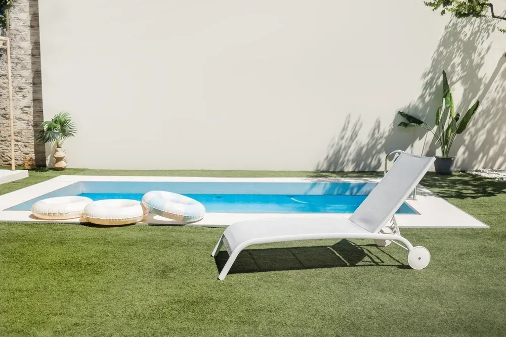 White lounge chair by a small, rectangular backyard pool on a sunny day — Sun Cool Pools & Spas in Gympie, QLD