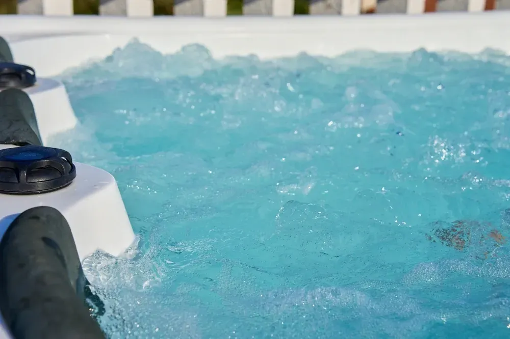 A Close-up View of Bubbling, Light Blue Water Inside a Hot Tub With White Trim — Sun Cool Pools & Spas in Bundaberg, QLD