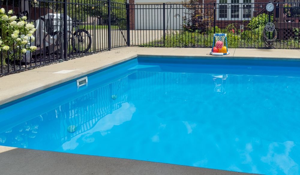 A Bright Blue Swimming Pool With a Concrete Deck — Sun Cool Pools & Spas in Maryborough, QLD