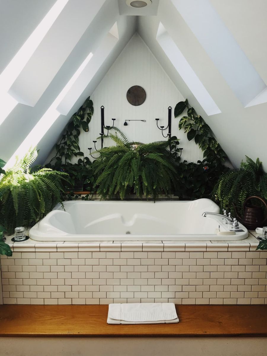 A White Tiled Bathtub Sits Beneath a Slanted Attic Ceiling With Skylights — Sun Cool Pools & Spas in Maryborough, QLD