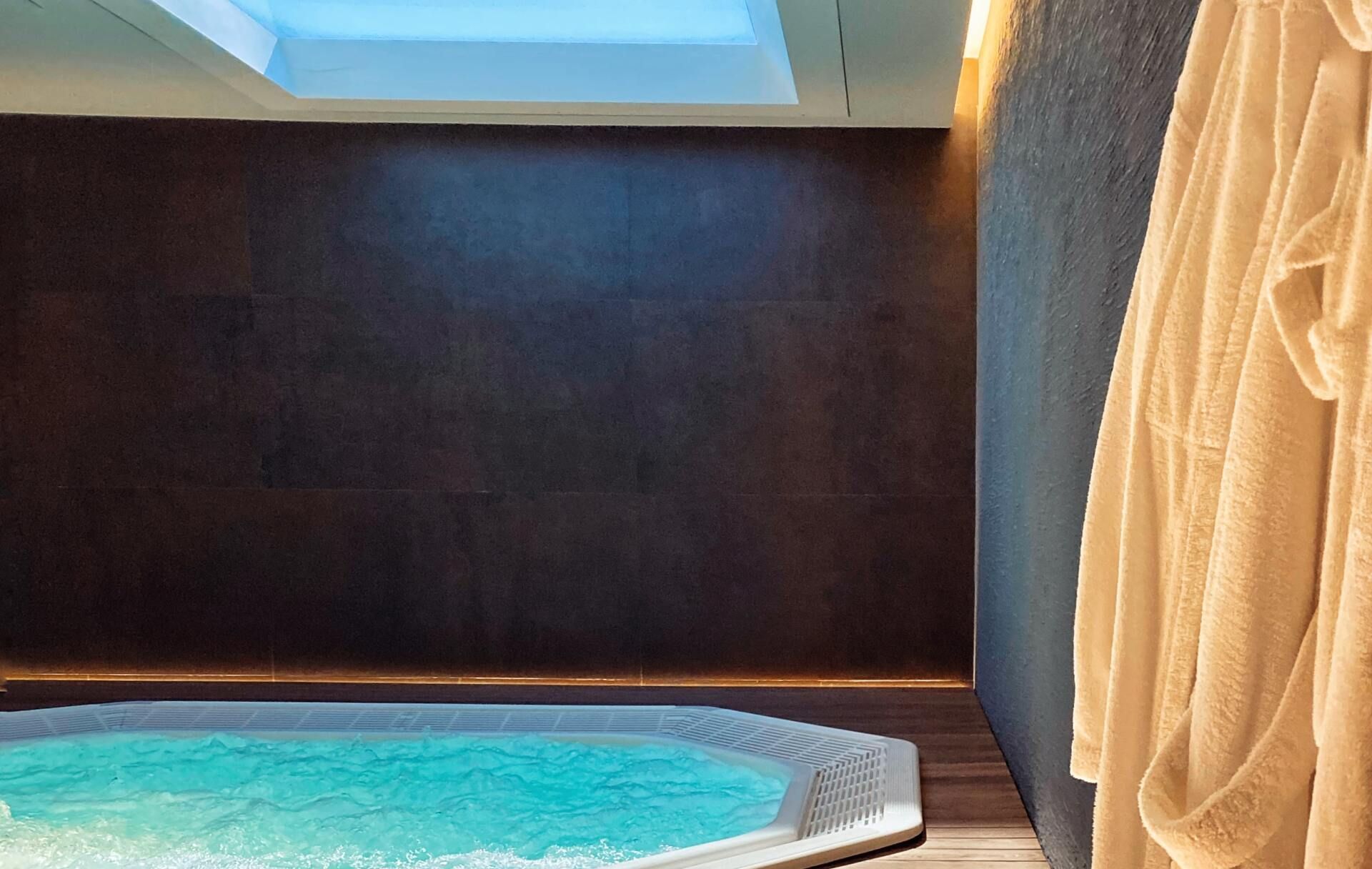 A Private Spa Room Features a Bright Turquoise Hot Tub Beneath a Skylight — Sun Cool Pools & Spas in Maryborough, QLD