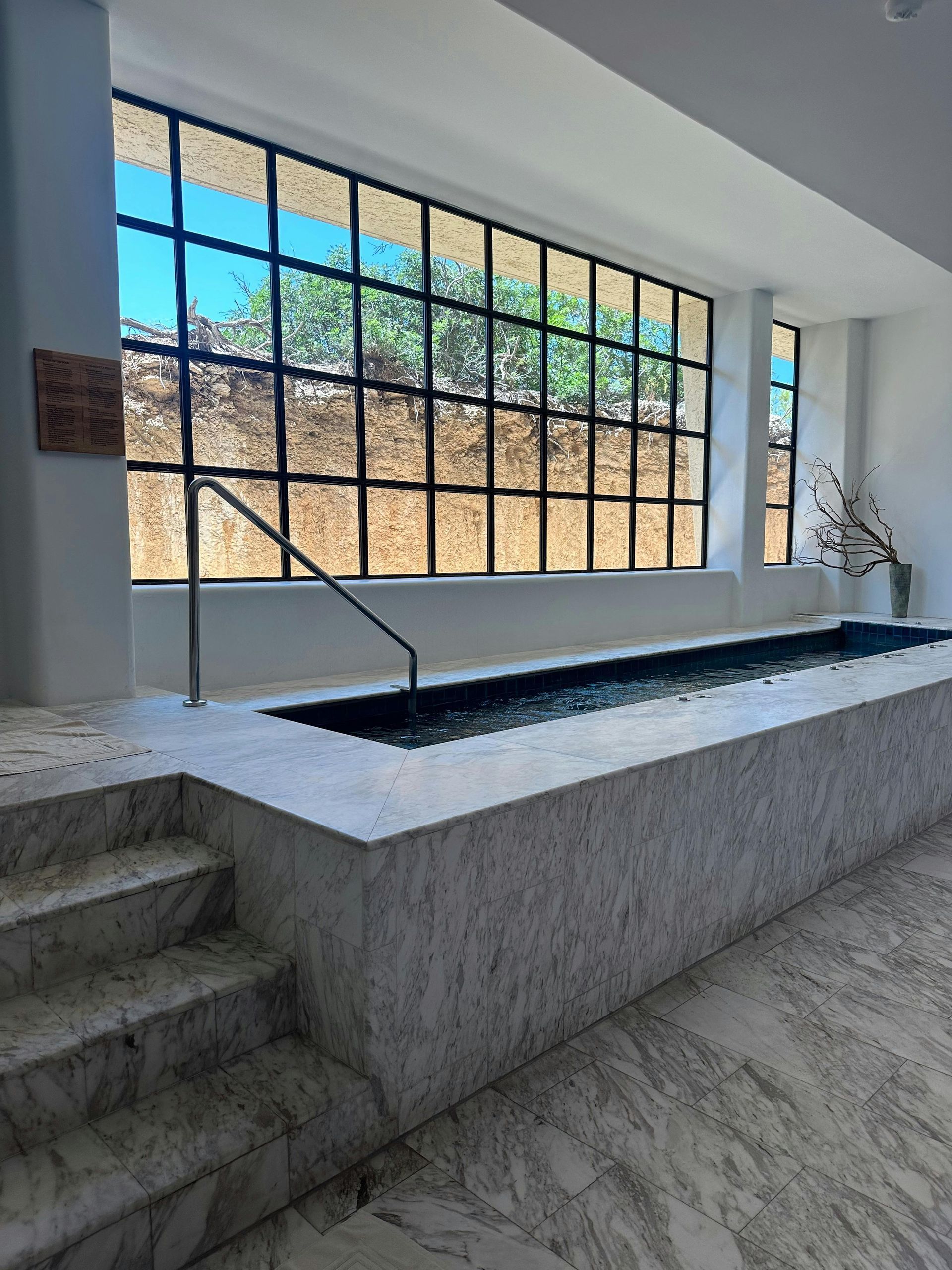 Indoor Stone Pool With Steps, Black Handrails, and Large Grid Windows — Sun Cool Pools & Spas in Maryborough, QLD