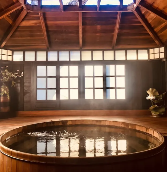A Steaming Wooden Circular Hot Tub Inside a Rustic Room — Sun Cool Pools & Spas in Hervey Bay, QLD