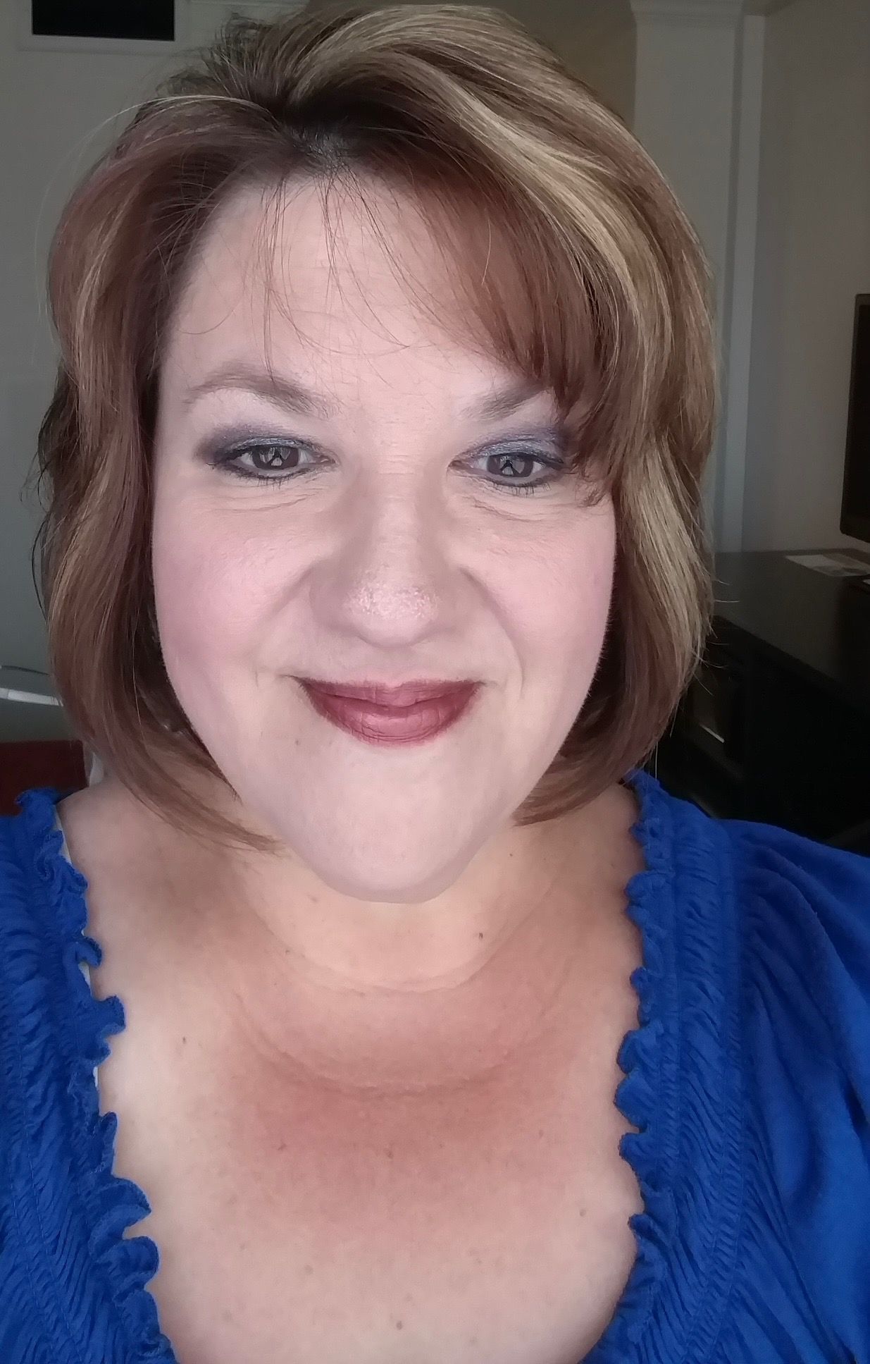 Portrait of a smiling woman with short brown hair wearing a blue top indoors