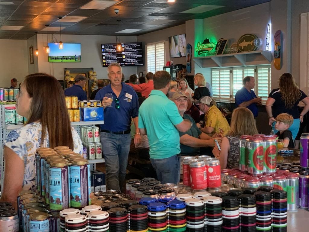 People browsing snacks and drinks inside a busy convenience store with a counter and TV screens