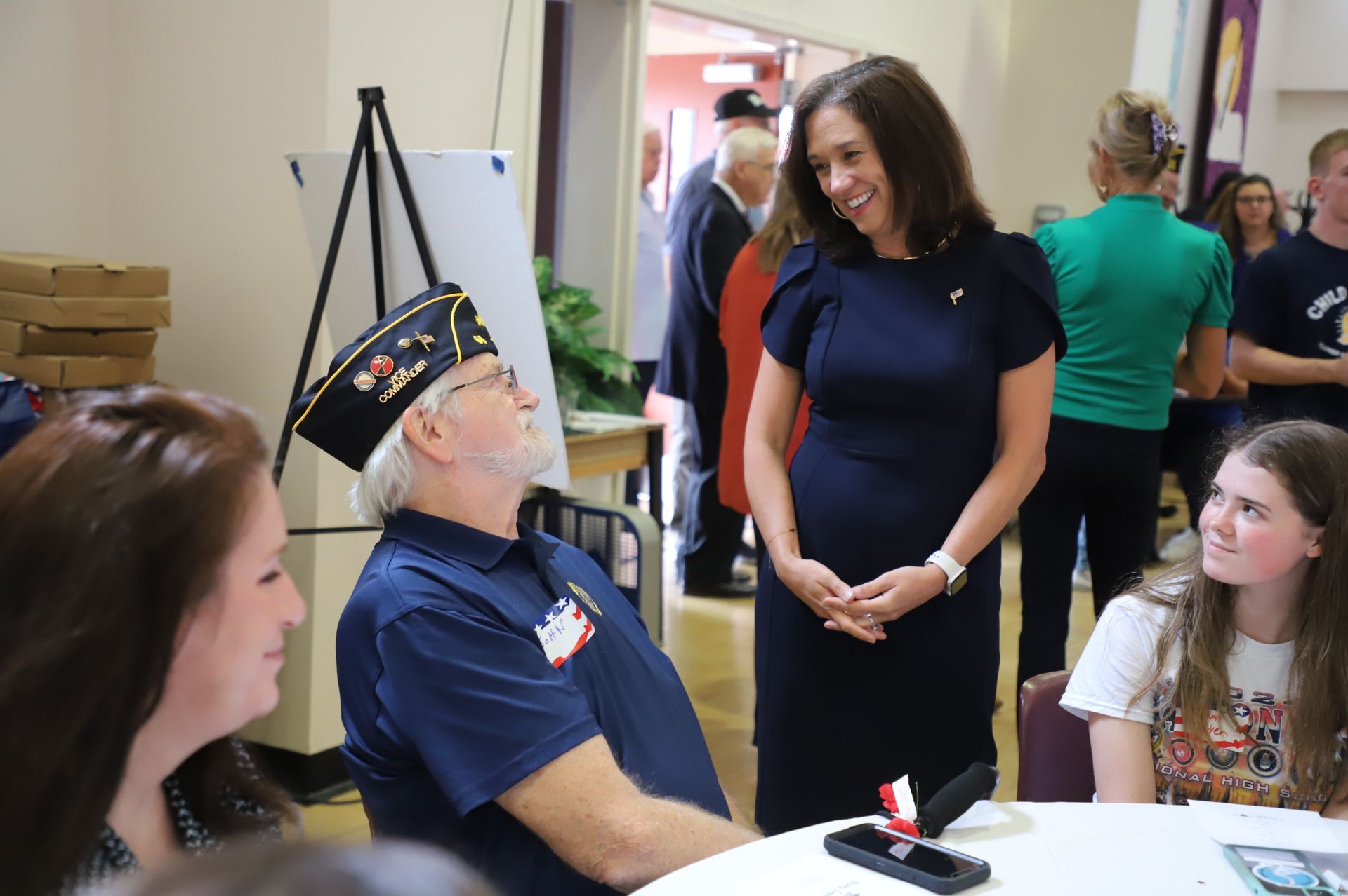 Veteran in cap talking with smiling woman at a table during a community event