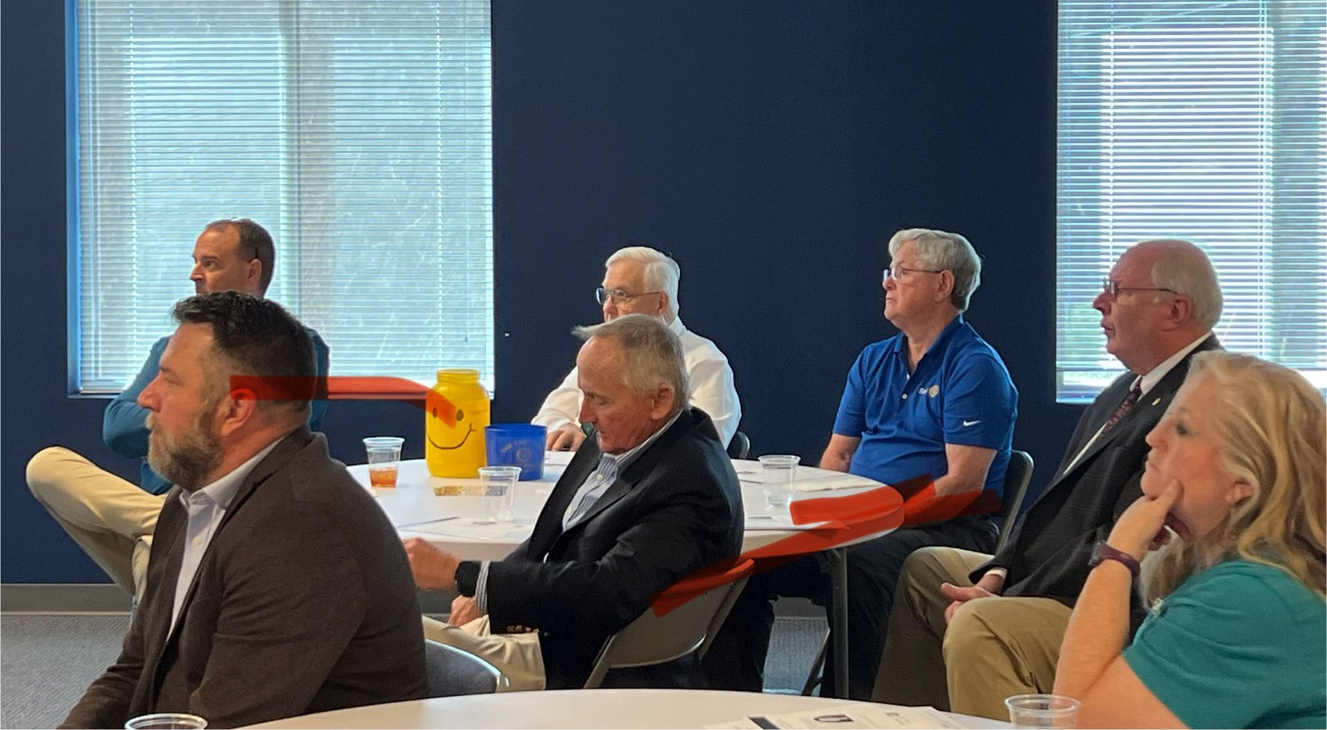 Audience seated in a conference room, listening attentively during a presentation