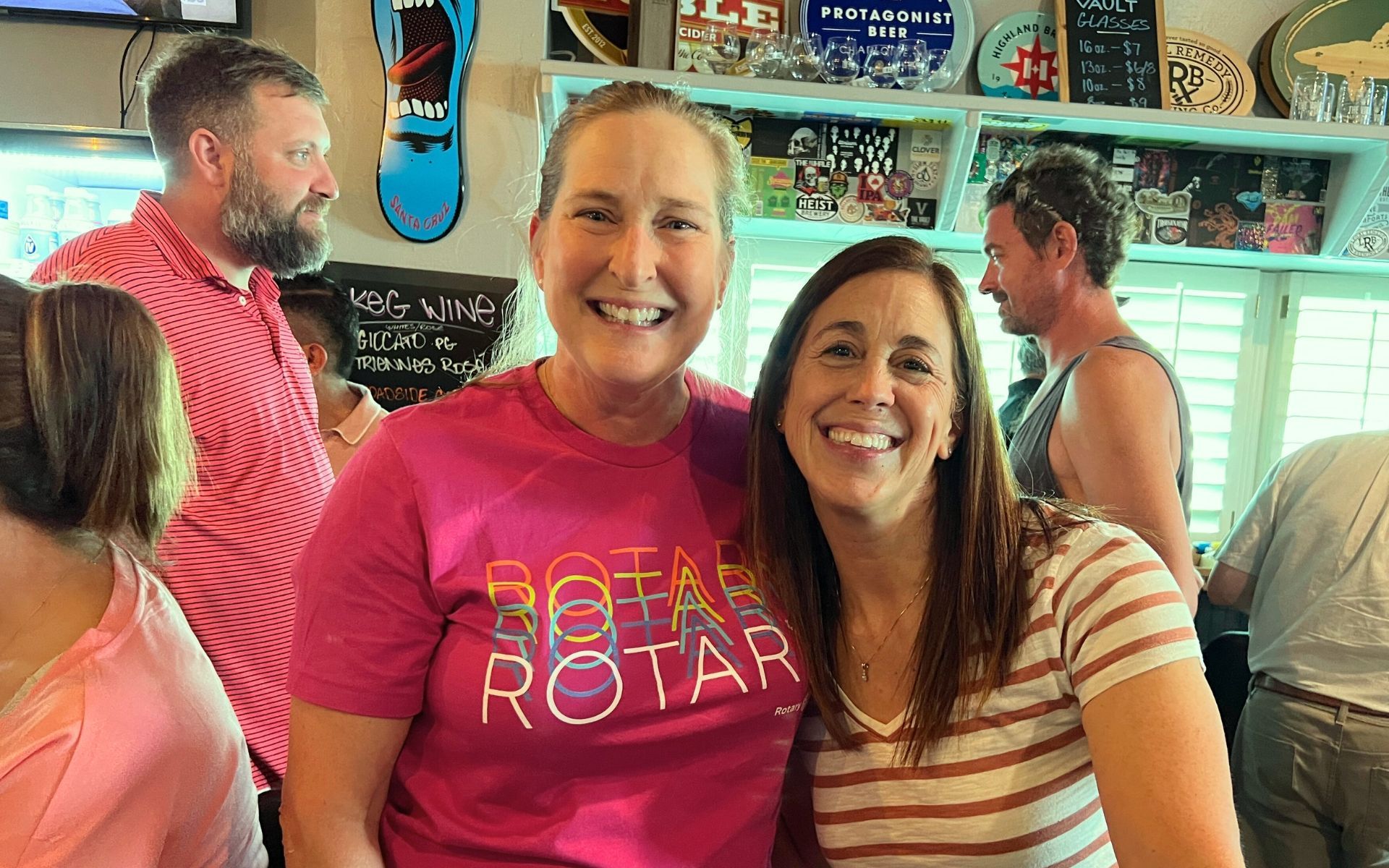 Three smiling people in a colorful shop, with skateboards and artwork on the wall.