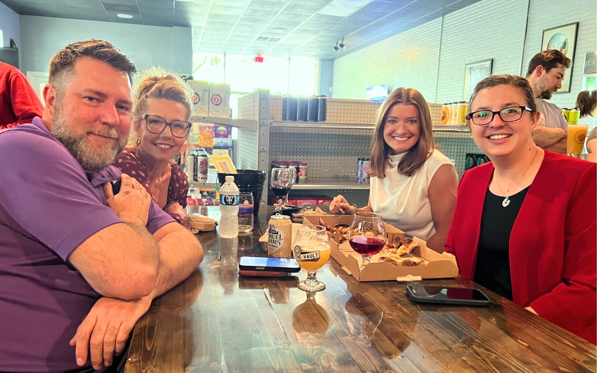 Four people smiling at a restaurant table with drinks and a dessert tray